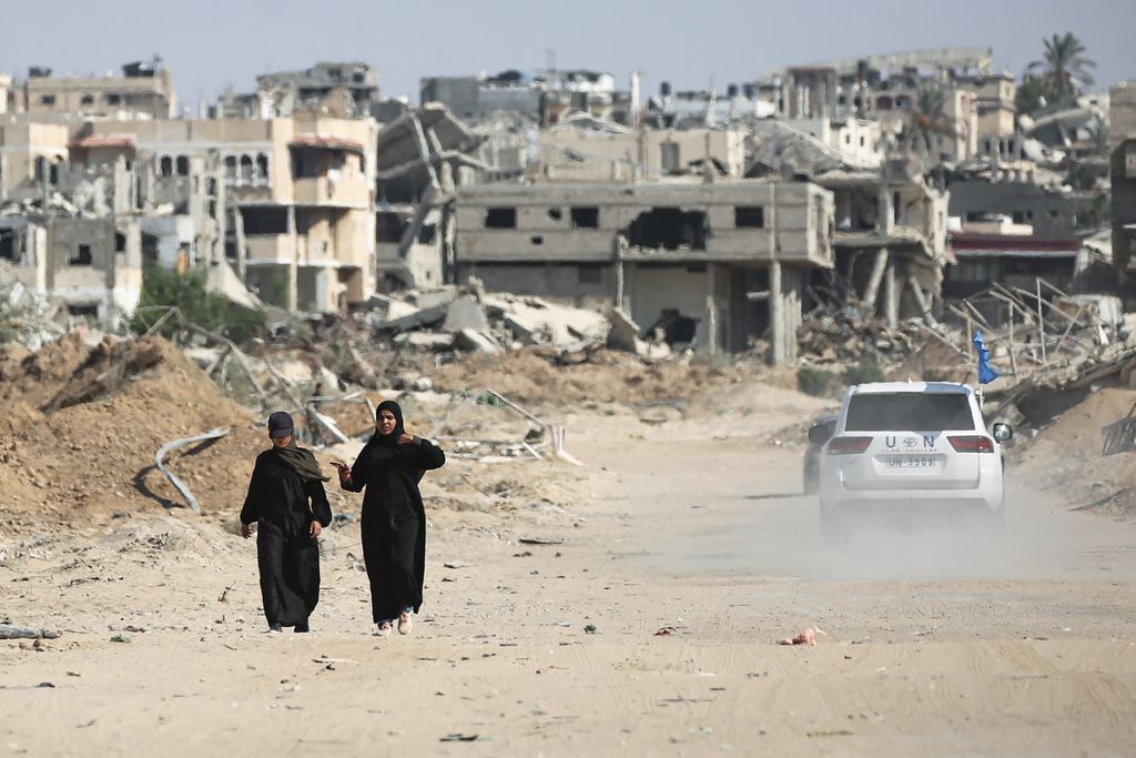 Palestinians walk past destruction and a UN vehicle in Khan Yunis in the southern Gaza Strip on September 10, 2024, amid the ongoing war between Israel and Palestinian militant group Hamas. (Photo by Eyad BABA / AFP)