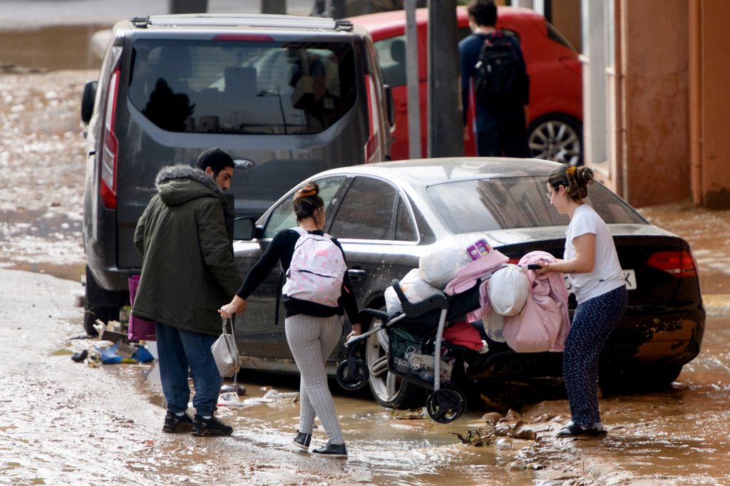 Residents walk in a street covered in mud following floods in Valencia's De La Torre neighbourhood, eastern Spain, on October 30, 2024. Floods triggered by torrential rains in Spain's eastern Valencia region has left at least 62 people dead, rescue services said on October 30. (Photo by Ruben FENOLLOSA / AFP)