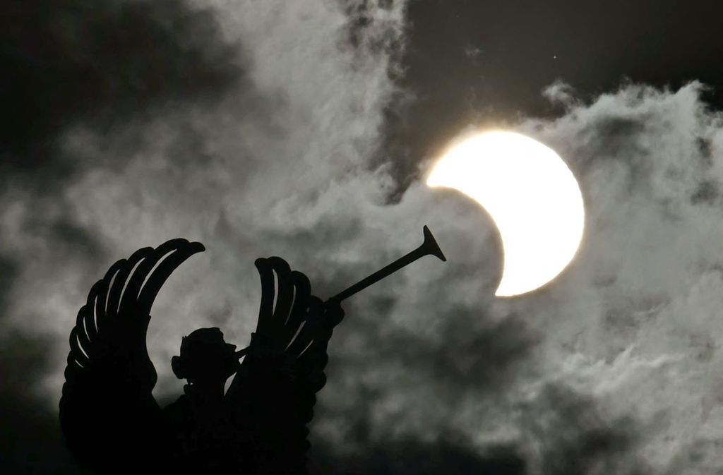 Partial view of the solar annular eclipse is pictured behind an Angels monument at the National Congress building in Buenos Aires, taken on October 2, 2024. Part of the southern hemisphere will witness this Wednesday an annular eclipse that will occur when the Moon almost totally covers the Sun, leaving a luminous ring visible, a spectacle that will be seen in its maximum splendor from the Chilean and Argentinean Patagonia. (Photo by Luis ROBAYO / AFP)