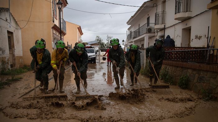 Members of the INFOCA (Andalusia Fire Prevention and Extinction Plan) clean a flooded street in Cartama, near Malaga, on October 30, 2024, after heavy rains hit southern Spain. Heavy rains hit southern Spain on October 30, 2024. Floods in eastern Valencia region has left at least 70 people dead. (Photo by JORGE GUERRERO / AFP)