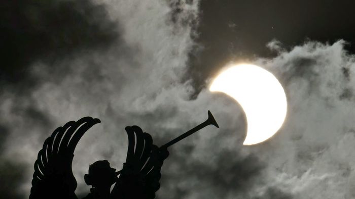 Partial view of the solar annular eclipse is pictured behind an Angels monument at the National Congress building in Buenos Aires, taken on October 2, 2024. Part of the southern hemisphere will witness this Wednesday an annular eclipse that will occur when the Moon almost totally covers the Sun, leaving a luminous ring visible, a spectacle that will be seen in its maximum splendor from the Chilean and Argentinean Patagonia. (Photo by Luis ROBAYO / AFP)