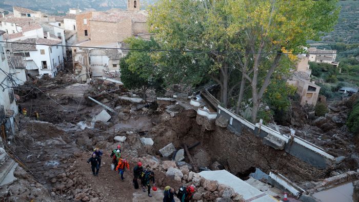 Emergency services staff members walk in a street devastated following floods in Letur, southwest of Valencia, eastern Spain, on October 30, 2024. Floods triggered by torrential rains in Spain's eastern Valencia region has left at least 70 people dead, rescue services said on October 30. (Photo by OSCAR DEL POZO / AFP)