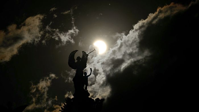 Partial view of the solar annular eclipse is pictured behind an Angels monument at the National Congress building in Buenos Aires, taken on October 2, 2024. Part of the southern hemisphere will witness this Wednesday an annular eclipse that will occur when the Moon almost totally covers the Sun, leaving a luminous ring visible, a spectacle that will be seen in its maximum splendor from the Chilean and Argentinean Patagonia. (Photo by Luis ROBAYO / AFP)