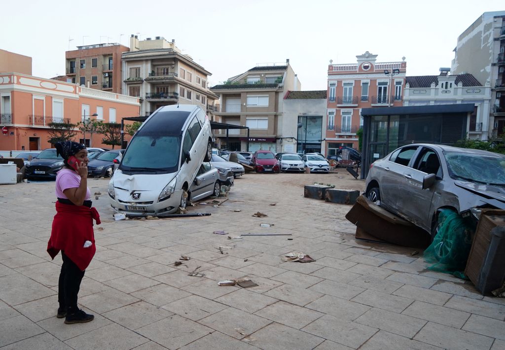 A resident talks on phone next to piled up cars following deadly floods in Alfafar neighbourhood, south of Valencia, eastern Spain, on October 30, 2024. Floods triggered by torrential rains in Spain's eastern Valencia region has left at least 70 people dead, rescue services said on October 30. (Photo by Manaure Quintero / AFP)