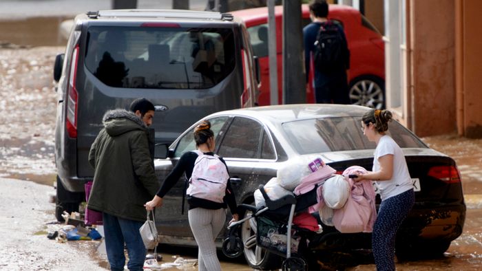 Residents walk in a street covered in mud following floods in Valencia's De La Torre neighbourhood, eastern Spain, on October 30, 2024. Floods triggered by torrential rains in Spain's eastern Valencia region has left at least 62 people dead, rescue services said on October 30. (Photo by Ruben FENOLLOSA / AFP)