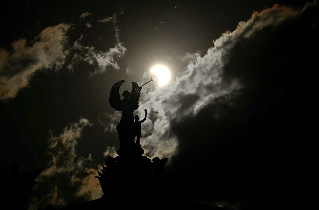 Partial view of the solar annular eclipse is pictured behind an Angels monument at the National Congress building in Buenos Aires, taken on October 2, 2024. Part of the southern hemisphere will witness this Wednesday an annular eclipse that will occur when the Moon almost totally covers the Sun, leaving a luminous ring visible, a spectacle that will be seen in its maximum splendor from the Chilean and Argentinean Patagonia. (Photo by Luis ROBAYO / AFP)