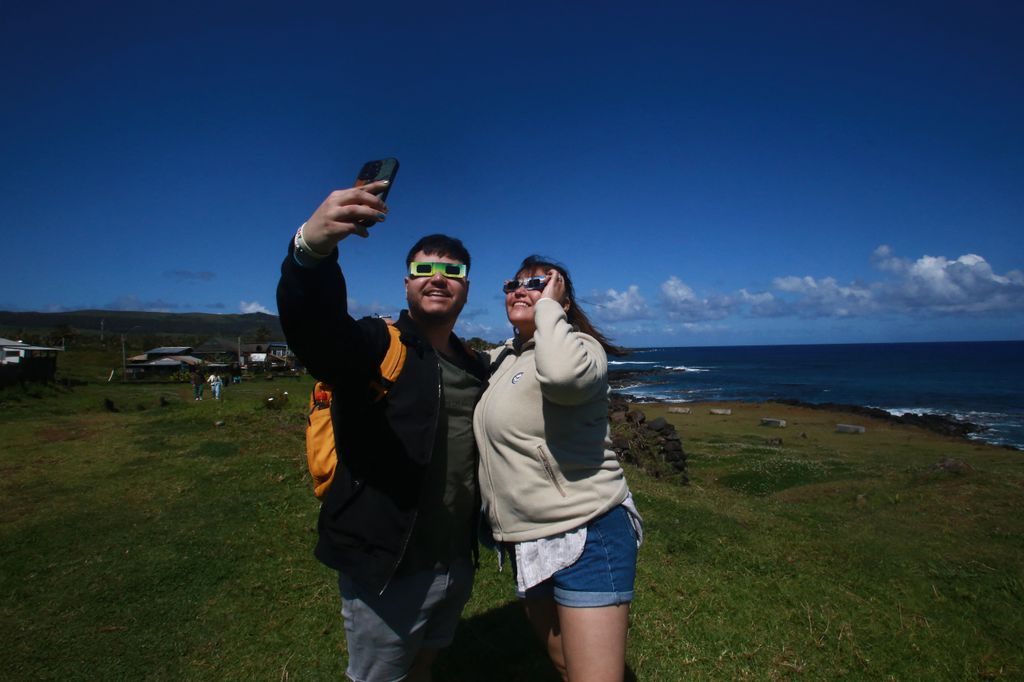 A couple of tourists take a selfie as they prepare to view the annular solar eclipse at Isla de Pascua in the Pacific Ocean, Chile, on October 2, 2024. Part of the southern hemisphere will witness this Wednesday an annular eclipse that will occur when the Moon almost totally covers the Sun, leaving a luminous ring visible, a spectacle that will be seen in its maximum splendor from the Chilean and Argentinean Patagonia. (Photo by Jonathan MARTINS / AFP)