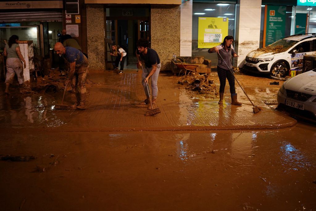 Residents clean the pavement following deadly floods in Valencia's De La Torre neighbourhood, south of Valencia, eastern Spain, on October 30, 2024. Floods triggered by torrential rains in Spain's eastern Valencia region has left at least 70 people dead, rescue services said on October 30. (Photo by Manaure Quintero / AFP)