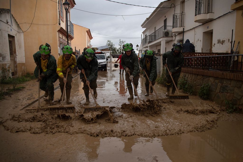 Members of the INFOCA (Andalusia Fire Prevention and Extinction Plan) clean a flooded street in Cartama, near Malaga, on October 30, 2024, after heavy rains hit southern Spain. Heavy rains hit southern Spain on October 30, 2024. Floods in eastern Valencia region has left at least 70 people dead. (Photo by JORGE GUERRERO / AFP)