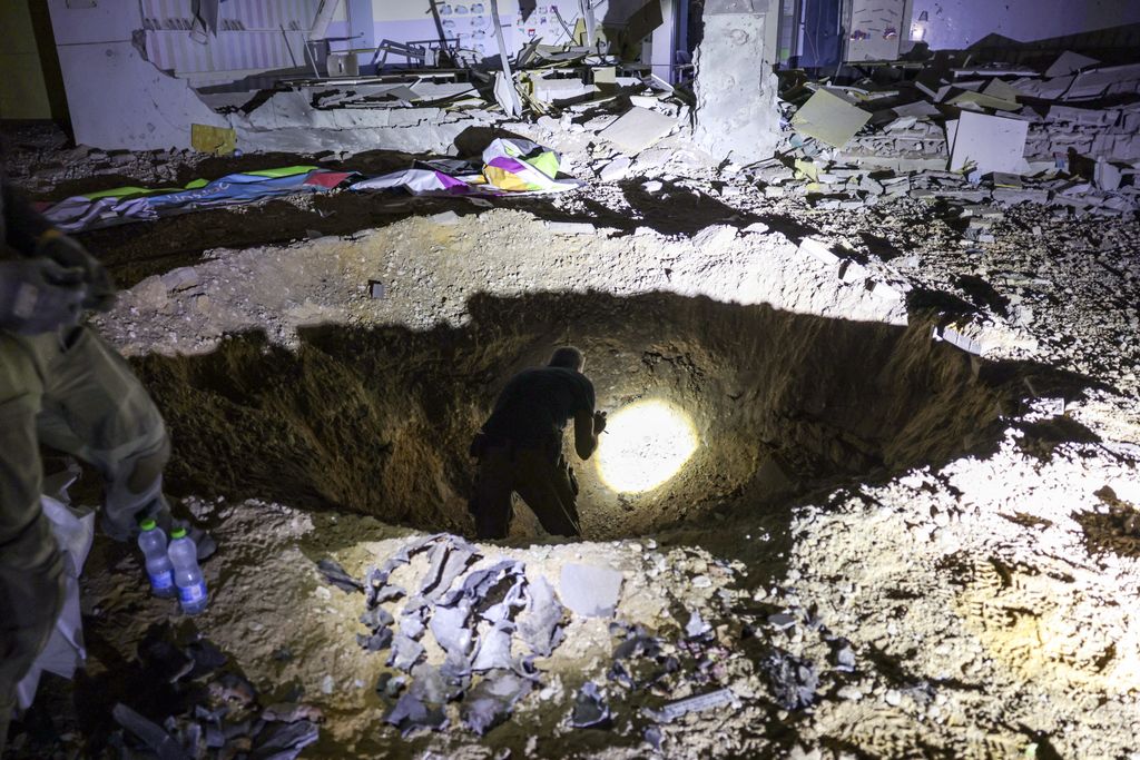 Members of Israel's Home Front Command and police forces inspect a crater left by an exploded projectile at a heavily-damaged school building in Israel's southern city of Gedera on October 1, 2024, after Iran launched a barrage of missiles at Israel in response to the killings of Lebanese Hezbollah leader Nasrallah and other Iran-backed militants. Reports said Iran fired between 150 and 200 missiles in the attack, the country's second on Israel after a missile and drone attack in April in response to a deadly Israeli air strike on the Iranian consulate in Damascus. (Photo by Menahem KAHANA / AFP)