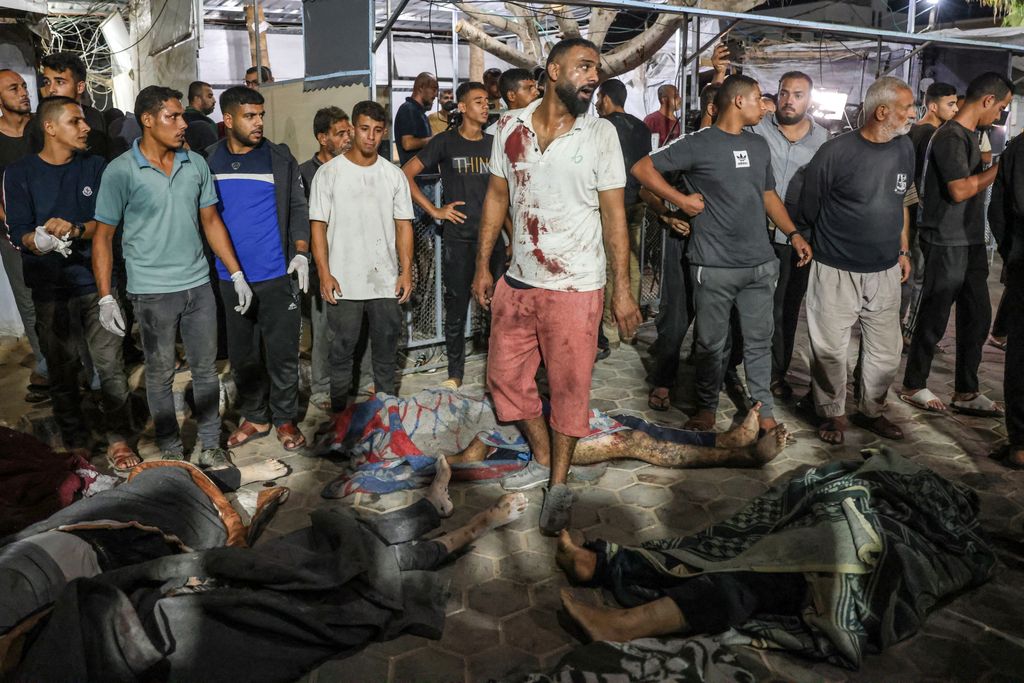 EDITORS NOTE: Graphic content / Bodies of victims of an Israeli strike that targeted a mosque-turned-shelter in Deir al-Balah in the central Gaza Strip, are laid in the courtyard of the al-Aqsa Martyrs hospital for identification during the night of October 6, 2024, amid the ongoing war between Israel and the Palestinian Hamas movement. Gaza's civil defence agency said on October 6 that an Israeli strike on the mosque-turned-shelter in central Deir al-Balah killed 21 people, while Israel's military said it had targeted Hamas militants. (Photo by BASHAR TALEB / AFP)