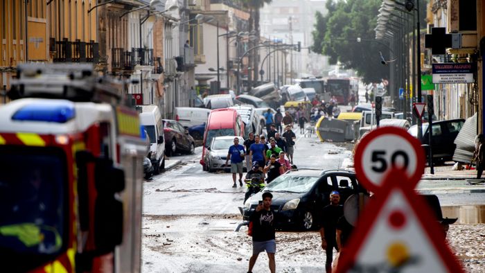 Residents walk next to piled up cars in a street covered in mud following floods in Valencia's De La Torre neighbourhood, eastern Spain, on October 30, 2024. Floods triggered by torrential rains in Spain's eastern Valencia region has left at least 62 people dead, rescue services said on October 30. (Photo by Ruben FENOLLOSA / AFP)