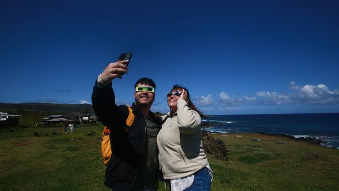 A couple of tourists take a selfie as they prepare to view the annular solar eclipse at Isla de Pascua in the Pacific Ocean, Chile, on October 2, 2024. Part of the southern hemisphere will witness this Wednesday an annular eclipse that will occur when the Moon almost totally covers the Sun, leaving a luminous ring visible, a spectacle that will be seen in its maximum splendor from the Chilean and Argentinean Patagonia. (Photo by Jonathan MARTINS / AFP)