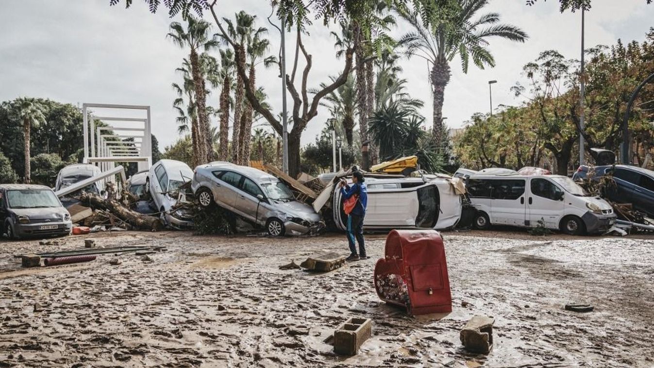 Egy nő áll az összetört autók mellett a heves esőzések miatt bekövetkezett katasztrofális árvíz után a spanyolországi Valencia Sedavi kerületében