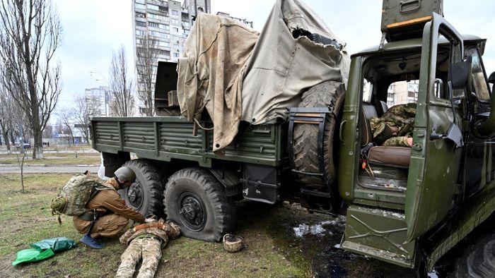 EDITORS NOTE: Graphic content / An Ukrainian military medic (L) examines the body of a Russian serviceman wearing a Ukranian service uniform lying beside a vehicle after he and members from a raiding party were shot during a skirmish in the Ukrainian capital of Kyiv on February 25, 2022, according to Ukrainian service personnel at the scene. Russian forces are approaching Kyiv from the north and northeast, Ukraine's army said, with rising fears the capital could fall on the second day of Moscow's offensive. (Photo by Sergei SUPINSKY / AFP)