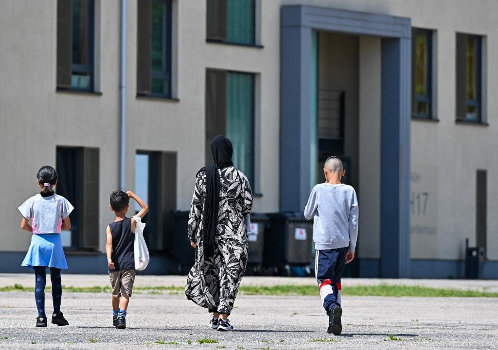 Egy migráns nő és három gyermeke átsétál a menedékkérők központi befogadó központja (ZABH) területén Brandenburg államban