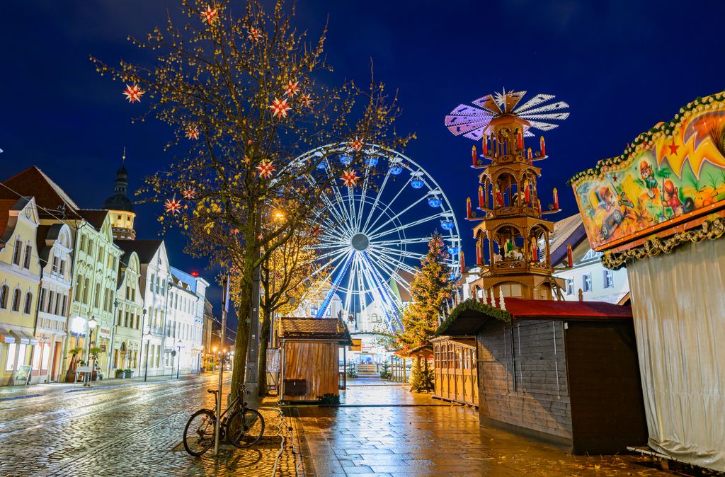 Cottbus Christmas market before opening20 November 2024, Brandenburg, Cottbus: A Ferris wheel and a pyramid stand together with closed stalls at the Cottbus Christmas Market of 1000 Stars in the evening. The Christmas market on the Altmarkt in Cottbus city center will open on 25.11.2024. Photo: Patrick Pleul/dpa/ZB (Photo by PATRICK PLEUL / DPA / dpa Picture-Alliance via AFP)