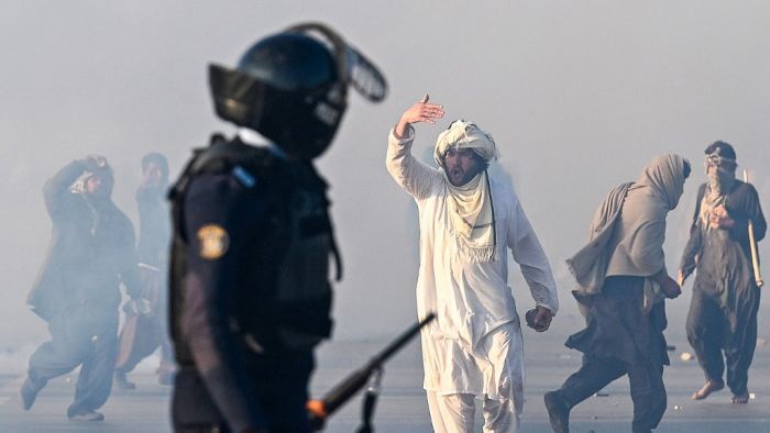 A supporter of Pakistan Tehreek-e-Insaf (PTI) party gestures after tear gas was fired by the police to disperse the crowd during a protest to demand the release of former prime minister Imran Khan in Islamabad on November 26, 2024. Thousands of protestors calling for the release of Pakistan's jailed ex-prime minister Imran Khan defied roadblocks and tear gas to march to the gates of the nation's capital on November 26. (Photo by Aamir QURESHI / AFP)