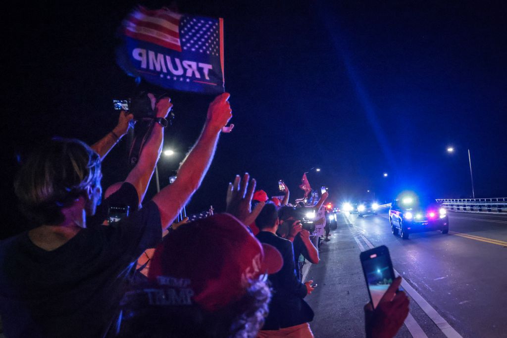 Supporters of former US president and Republican presidential candidate Donald Trump gesture as a motorcade drives near his Mar-a-Lago resort in Palm Beach, Florida, on Election Day, early on November 6, 2024. (Photo by Giorgio Viera / AFP)