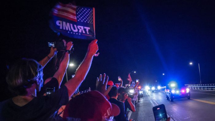 Supporters of former US president and Republican presidential candidate Donald Trump gesture as a motorcade drives near his Mar-a-Lago resort in Palm Beach, Florida, on Election Day, early on November 6, 2024. (Photo by Giorgio Viera / AFP)