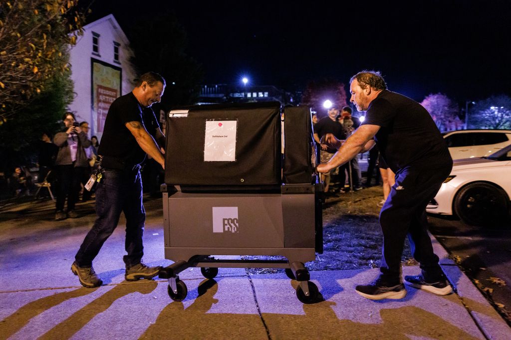 Workers deliver an additional voting machine to the polling location in the Banana Factory in the 3rd Ward of Bethlehem, Pennsylvania on November 5, 2024. The 3rd Ward polling location faced long lines from the start after one of the two voting machines broke early in the day and college students from Lehigh University flocked to cast their ballots causing as much as a six hour wait. (Photo by SAMUEL CORUM / AFP)