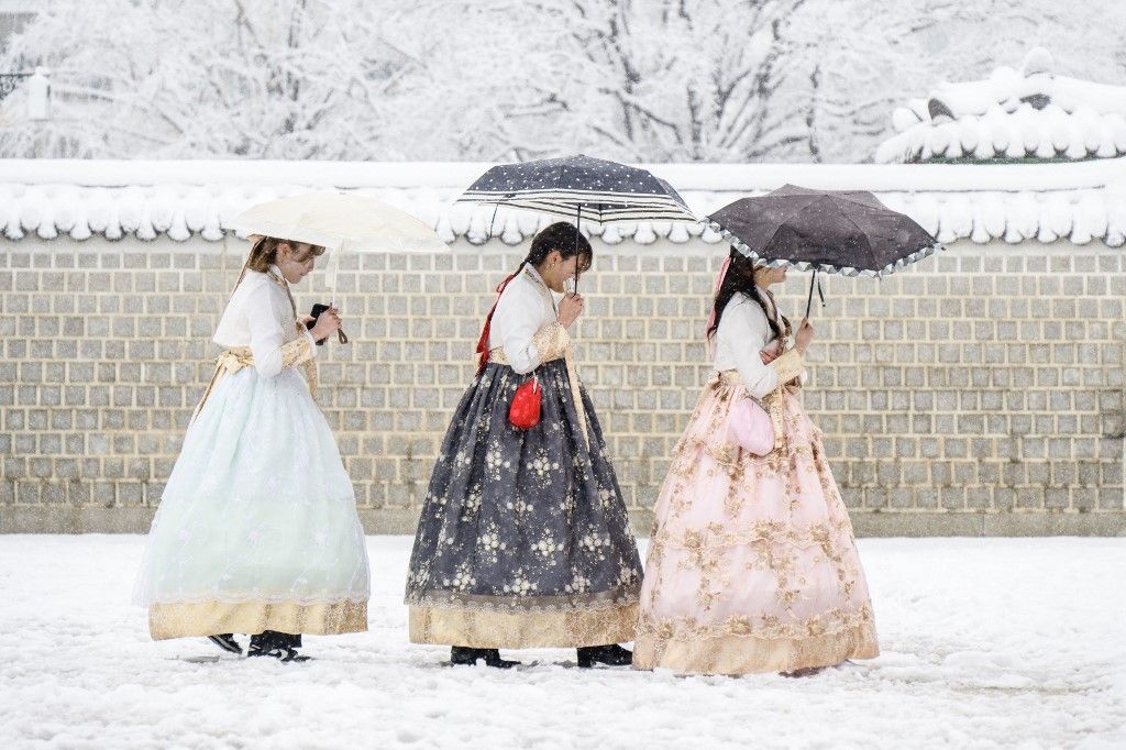 Visitors wearing traditional hanbok dresses are seen on the grounds of Gyeongbokgung Palace amid heavy snowfall in central Seoul on November 27, 2024. South Korea's capital was blanketed on November 27 by the heaviest November snowfall since records began over a century ago, the weather agency said. (Photo by ANTHONY WALLACE / AFP)