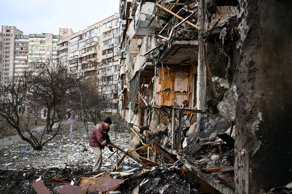 A man clears debris at a damaged residential building at Koshytsa Street, a suburb of the Ukrainian capital Kyiv, where a military shell allegedly hit, on February 25, 2022. Russian forces reached the outskirts of Kyiv on Friday as Ukrainian President Volodymyr Zelensky said the invading troops were targeting civilians and explosions could be heard in the besieged capital. Pre-dawn blasts in Kyiv set off a second day of violence after Russian President Vladimir Putin defied Western warnings to unleash a full-scale ground invasion and air assault on Thursday that quickly claimed dozens of lives and displaced at least 100,000 people. (Photo by Daniel LEAL / AFP)