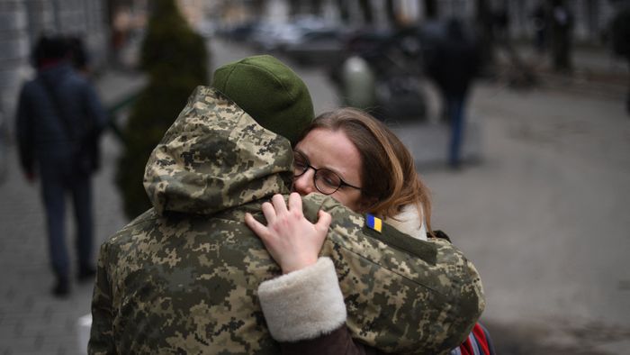 An Ukrainian soldier hugs his partner next to a military base where residents are queuing to join the army, in Lviv on March 2, 2022. Russia steps up its bombing campaign and missile strikes on Ukraine's cities on March 2, 2022. (Photo by Daniel LEAL / AFP)