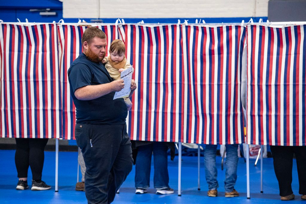 A person carries a baby with a filled out ballot after voting at the Green Street Community Center in Concord, New Hampshire, on November 5, 2024. (Photo by Joseph Prezioso / AFP)