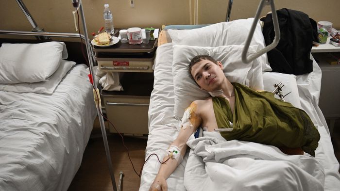 A 19 year old Ukrainian soldier named Yevhen lays in bed in a military hospital in Lviv on March 1, 2022, after being injured by a mine in the Luhansk region. (Photo by Daniel LEAL / AFP)