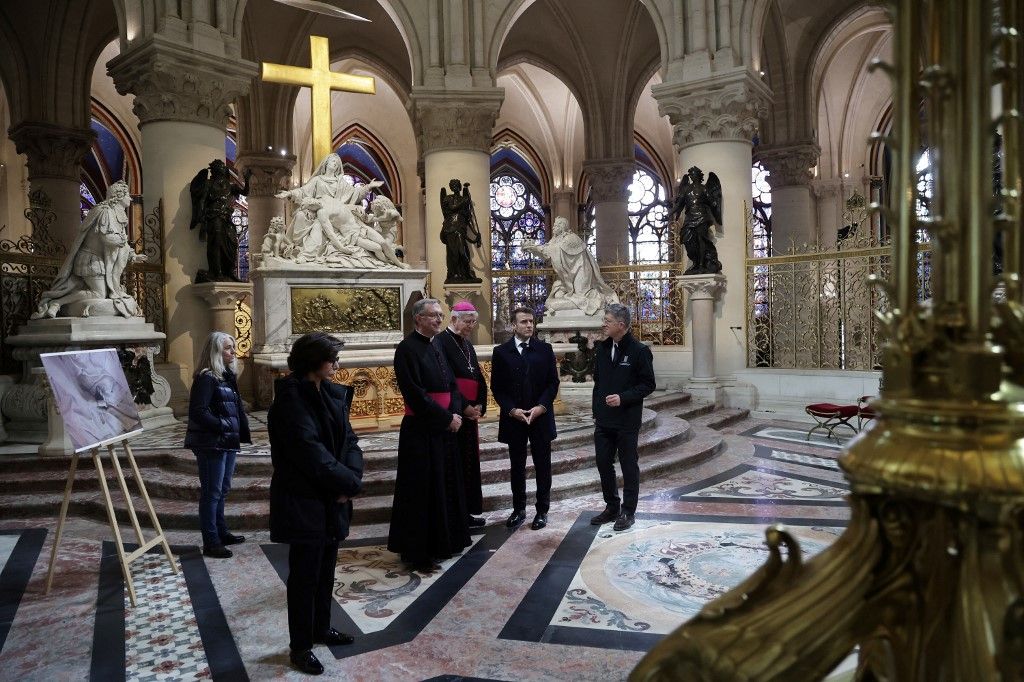 French President Emmanuel Macron (C-L) applauds with attendees, including workers of reconstruction of Notre-Dame de Paris cathedral, during his visit to the cathedral in Paris, on November 29, 2024. The Notre-Dame Cathedral is set to re-open early December 2024, with a planned weekend of ceremonies on December 7 and 8, 2024, five years after the 2019 fire which ravaged the world heritage landmark and toppled its spire. (Photo by Sarah Meyssonnier / POOL / AFP)