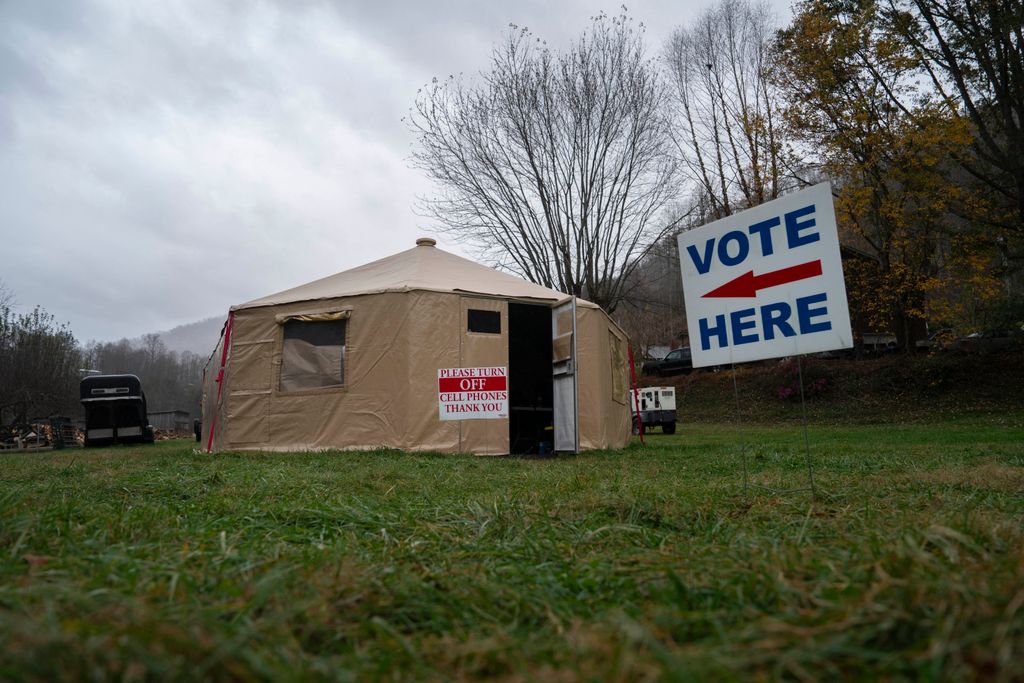 A 'vote here' sign is seen outside of a temporary voting site located in a tent that is also sheltering volunteer police due to damages caused by Hurricane Helene, on Election Day, November 5, 2024, in Burnsville, North Carolina. (Photo by Allison Joyce / AFP)