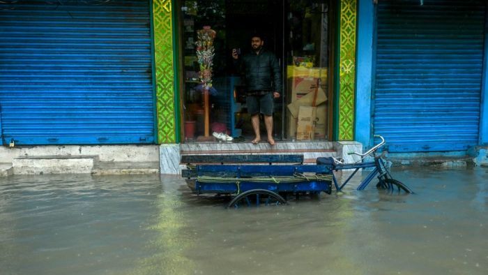 A man stands at his shop along a flooded street as it rains ahead of a cyclonic storm in Chennai on November 30, 2024. (Photo by R.Satish BABU / AFP)
