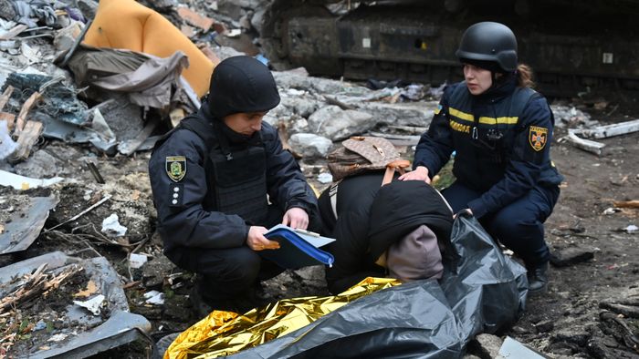 Ukrainian law enforcement officers comfort a woman crying over the body of her 15-year-old son following a missile attack in Kharkiv on October 31, 2024. Two children were among three killed in a Russian bombardment of an apartment building in Ukraine's second city of Kharkiv, with dozens more injured, the local governor said on October 31, 2024. (Photo by SERGEY BOBOK / AFP)