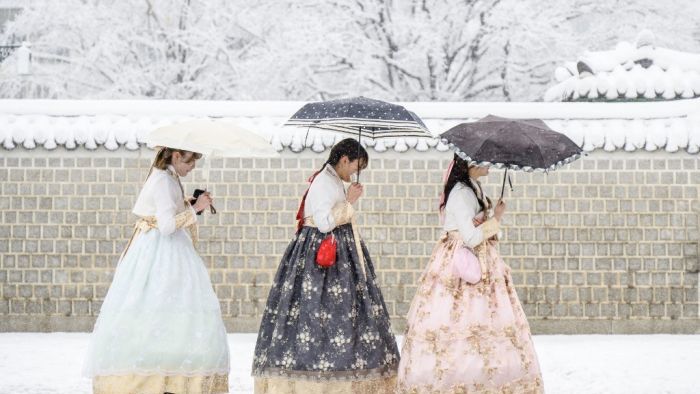 Visitors wearing traditional hanbok dresses are seen on the grounds of Gyeongbokgung Palace amid heavy snowfall in central Seoul on November 27, 2024. South Korea's capital was blanketed on November 27 by the heaviest November snowfall since records began over a century ago, the weather agency said. (Photo by ANTHONY WALLACE / AFP)