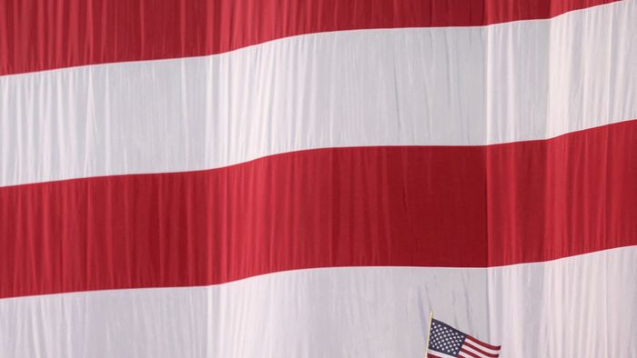 Supporters of US Vice President and Democratic presidential candidate Kamala Harris standing beneath a giant US flag wave small flags during an election night event at Howard University in Washington, DC, on November 5, 2024. (Photo by CHARLY TRIBALLEAU / AFP)