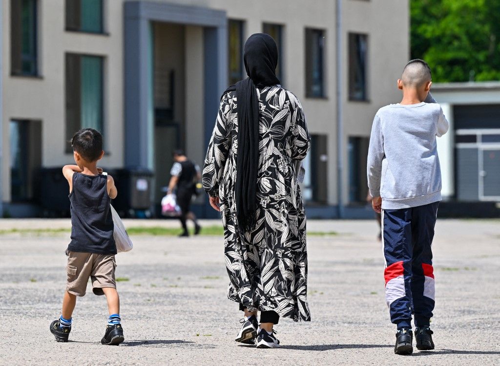 Egy migráns nő és két gyermeke átsétál a menedékkérők központi befogadó központja (ZABH) területén Brandenburg államban.