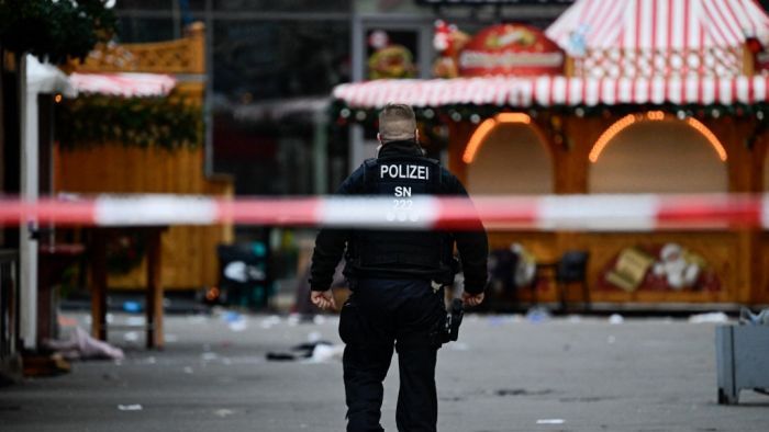 AFP or licensors/Police walks through an empty and closed off Christmas market where a car crashed into a crowd killing two and injuring more than 60 people the evening before, on early December 21, 2024 in Magdeburg, eastern Germany. At least one person was killed and 68 injured December 20, 2024 in a suspected attack on a Christmas market in the eastern Germany city of Magdeburg, local authorities said. (Photo by John MACDOUGALL / AFP)