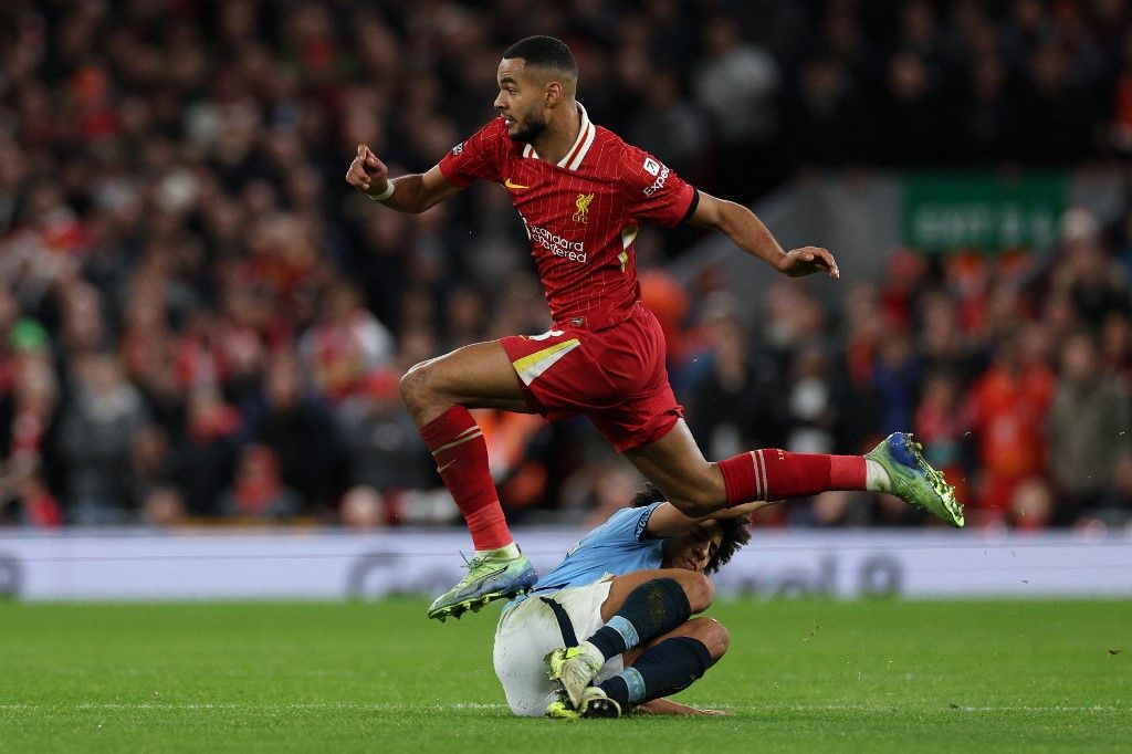 Liverpool's Dutch striker #18 Cody Gakpo jumps over Manchester City's English defender #82 Rico Lewis during the English Premier League football match between Liverpool and Manchester City at Anfield in Liverpool, north west England on December 1, 2024. (Photo by Adrian Dennis / AFP) / RESTRICTED TO EDITORIAL USE. No use with unauthorized audio, video, data, fixture lists, club/league logos or 'live' services. Online in-match use limited to 120 images. An additional 40 images may be used in extra time. No video emulation. Social media in-match use limited to 120 images. An additional 40 images may be used in extra time. No use in betting publications, games or single club/league/player publications. / 