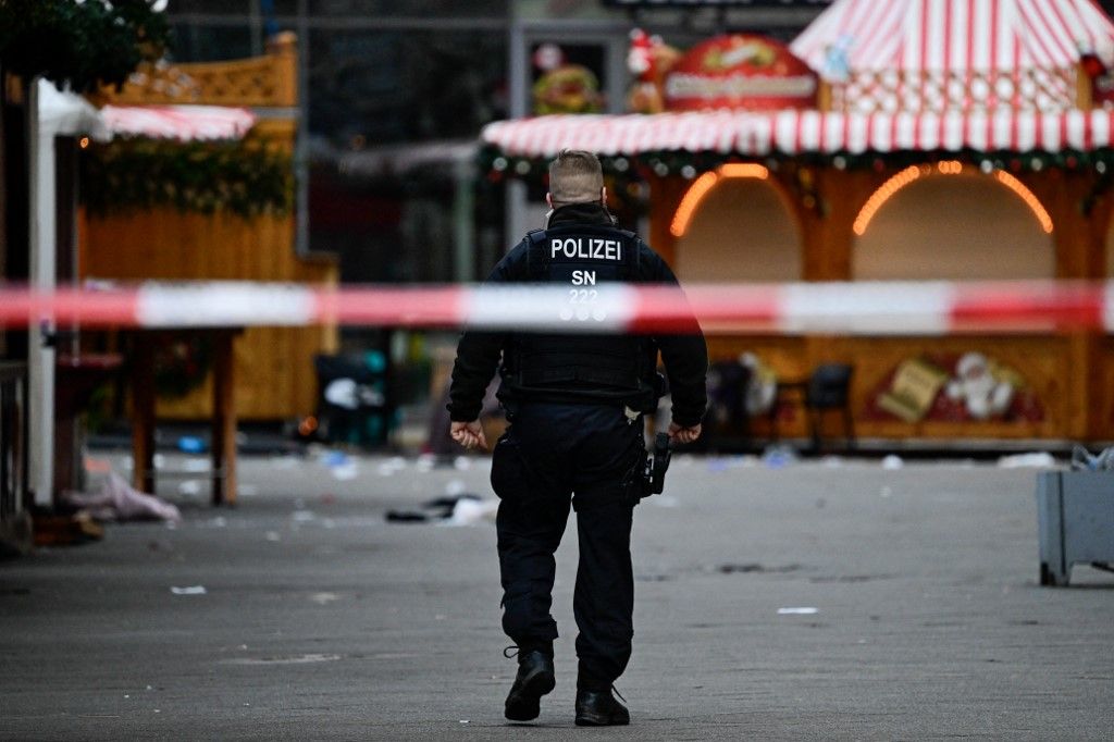 AFP or licensors/Police walks through an empty and closed off Christmas market where a car crashed into a crowd killing two and injuring more than 60 people the evening before, on early December 21, 2024 in Magdeburg, eastern Germany. At least one person was killed and 68 injured December 20, 2024 in a suspected attack on a Christmas market in the eastern Germany city of Magdeburg, local authorities said. (Photo by John MACDOUGALL / AFP)