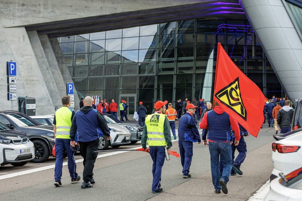 Employees of German carmaker BMW's Leipzig plant protest with the flag of the IG-Metall metal trade union in front of the plant's building in Leipzig, eastern Germany, on October 29, 2024.