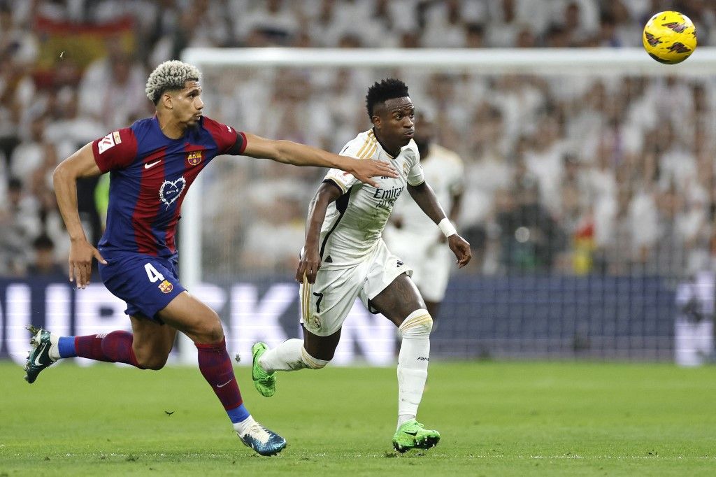 AFP or licensors/Barcelona's Uruguayan defender #04 Ronald Araujo and Real Madrid's Brazilian forward #07 Vinicius Junior vie for the ball during the Spanish league football match between Real Madrid CF and FC Barcelona at the Santiago Bernabeu stadium in Madrid on April 21, 2024. (Photo by OSCAR DEL POZO / AFP)