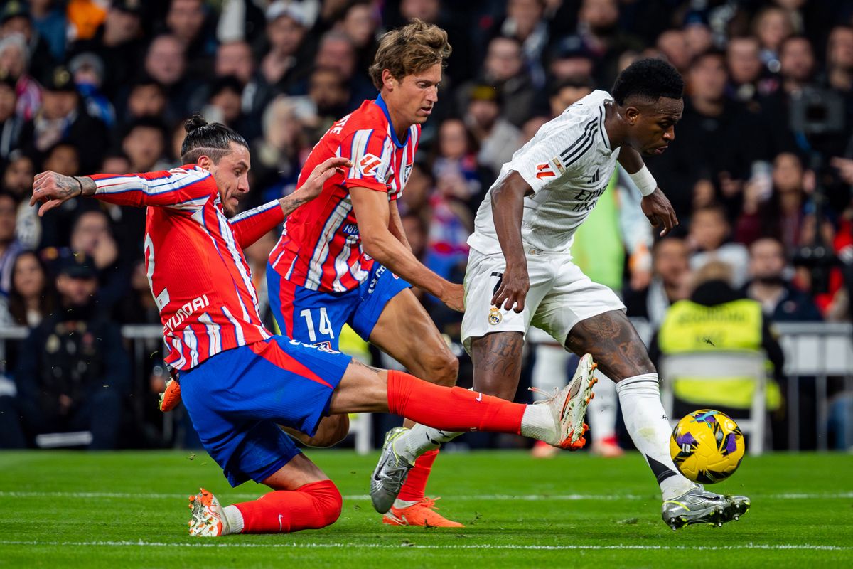 Vinicius Junior of Real Madrid CF (R) runs with the ball, defended by Jose Gimenez (L) and Marcos Llorente (C) of Atletico de Madrid during the La Liga EA Sports 2024/25 football match between Real Madrid CF and Atletico de Madrid at Estadio Santiago Bernabeu in Madrid, Spain, on February 8, 2025. (Photo by Alberto Gardin/NurPhoto) (Photo by Alberto Gardin / NurPhoto / NurPhoto via AFP)