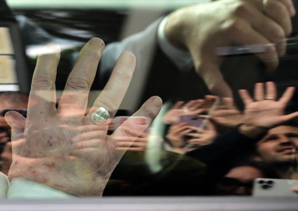 People reflect on the window of the car as Pope Francis leaves by the Gemelli hospital after a five weeks hospitalization for pneumonia, in Rome on March 23, 2025. Pope Francis is to leave hospital todayand return to his residence in the Vatican, where he