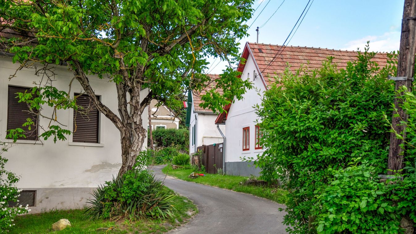 The road winds up alongside white village houses and trees