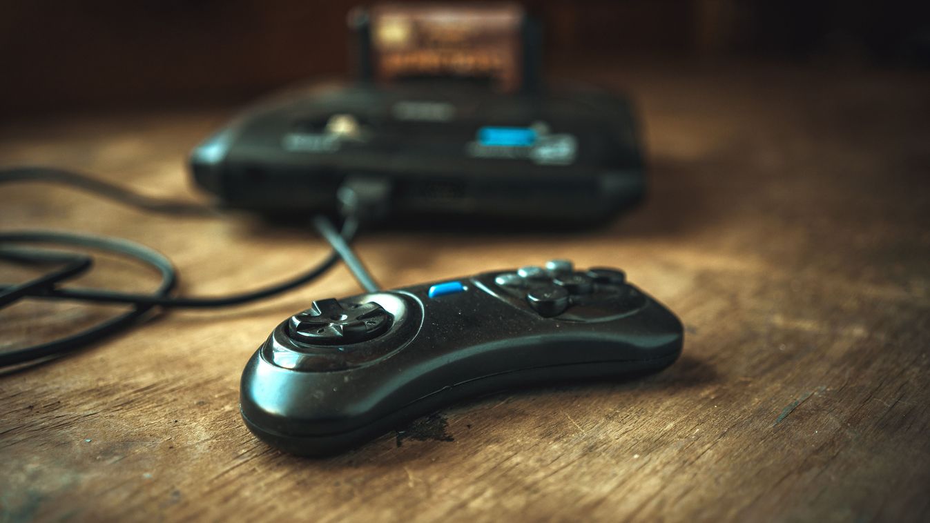 A game TV set-top box from the 90s on the table. Dusty 16-bit console.Old school.A joystick for playing the console.