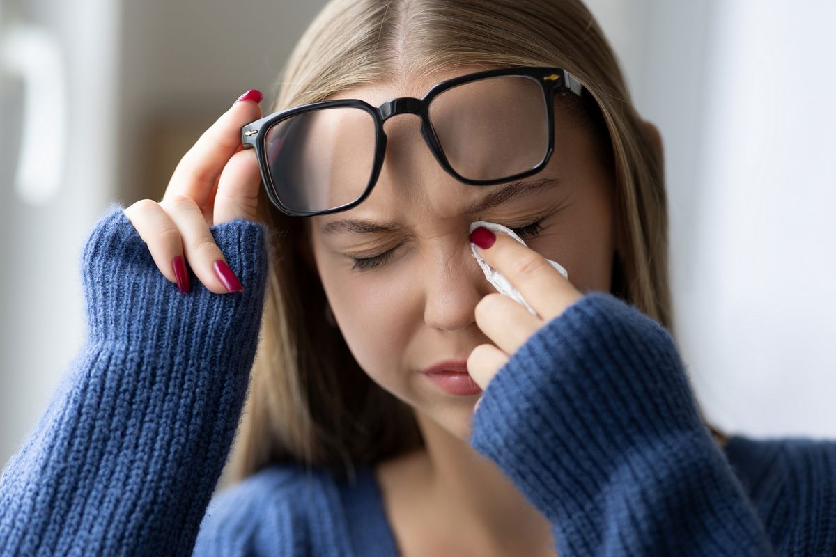 Young woman with glasses in a negative emotion and wiping her tears with a napkin