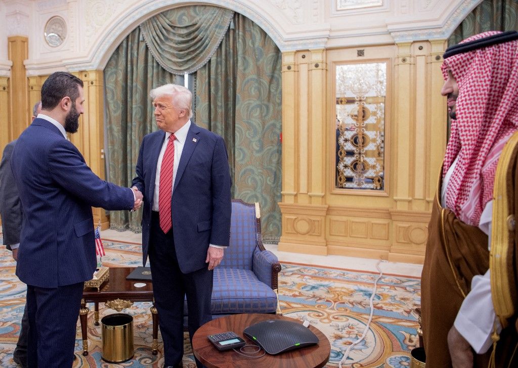A handout picture provided by the Saudi Royal Palace shows Saudi Crown Prince Mohammed bin Salman (R) watching as US President Donald Trump (C) shakes hands with Syria's interim president Ahmed al-Sharaa in Riyadh on May 14, 2025. Trump became the first US president in 25 years to meet a Syrian leader on May 14, after he offered sanctions relief in hopes of offering a new path to the war-battered country. (Photo by Bandar AL-JALOUD / Saudi Royal Palace / AFP) / RESTRICTED TO EDITORIAL USE - MANDATORY CREDIT "AFP PHOTO / SAUDI ROYAL PALACE / BANDAR AL-JALOUD" - NO MARKETING - NO ADVERTISING CAMPAIGNS - DISTRIBUTED AS A SERVICE TO CLIENTS