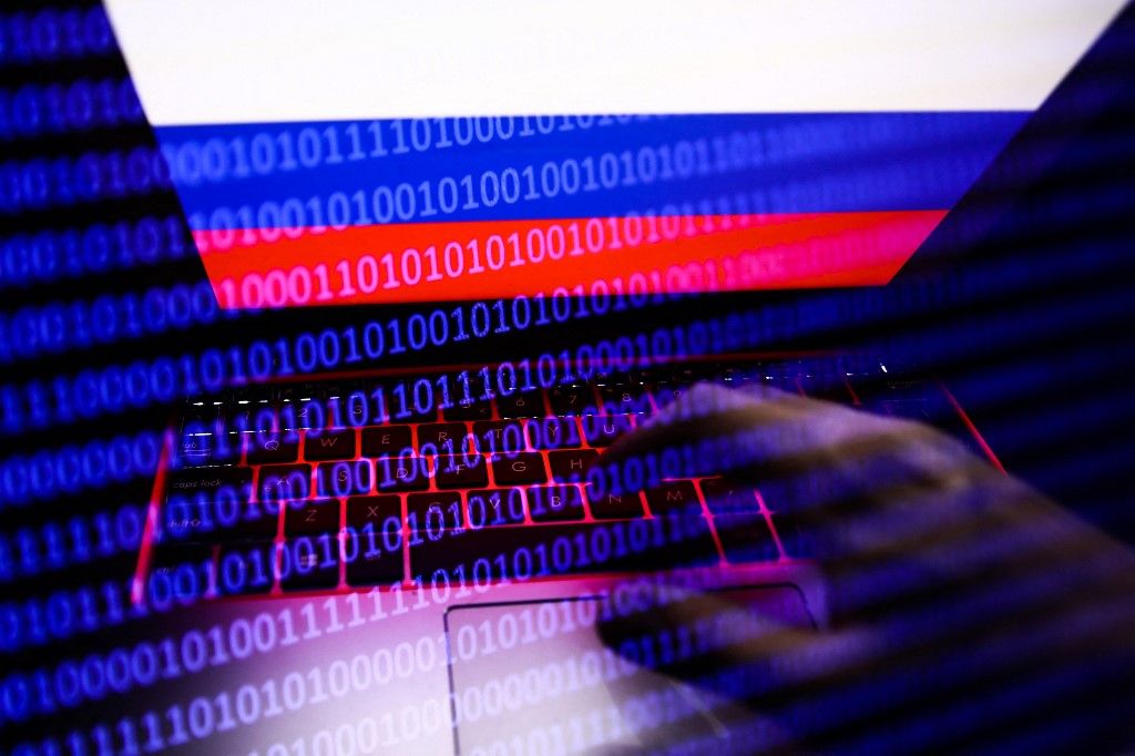 Russian flag displayed on a laptop screen and binary code code displayed on a screen are seen in this multiple exposure illustration photo taken in Krakow, Poland on February 16, 2022. (Photo illustration by Jakub Porzycki/NurPhoto) (Photo by Jakub Porzycki / NurPhoto / NurPhoto via AFP)