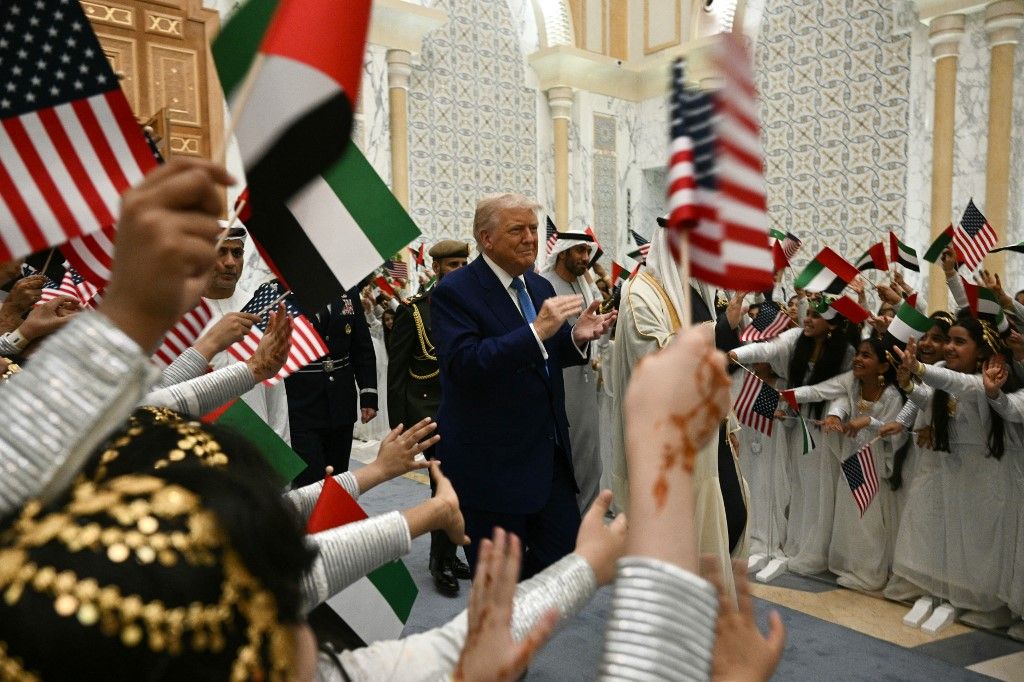 Gyerekek emirátusi és amerikai zászlókat lengetnek, amikor Donald Trump amerikai elnök megérkezik a Qasr Al-Watanba (a Nemzet Palotájába) Abu Dhabiban 2025. május 15-én. 